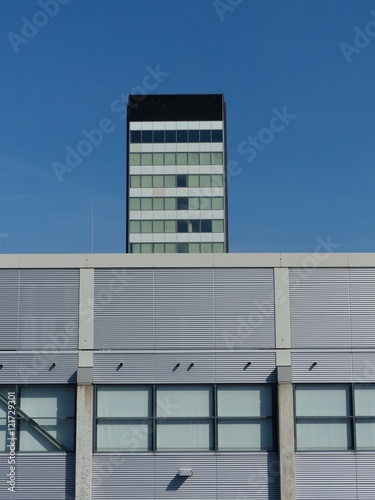 Hochhaus im Stil der Sechziger Jahre und moderne Messehalle vor blauem Himmel im Sonnenschein auf dem Messegelände der Köln Messe im Stadtteil Deutz in Köln am Rhein in Nordrhein-Westfalen photo