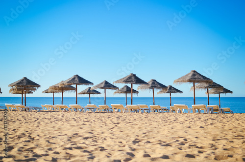 Blue sky and straw umbrella on a beautiful tropical beach background © aquar