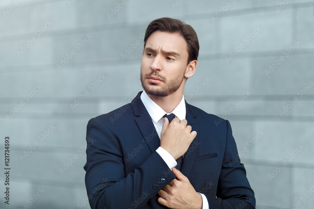 Elegant and successful. Confident young businessman correcting his necktie and looking away while standing outdoors
Elegant and successful. Confident young businessman correcting his necktie and looking away while standing outdoors