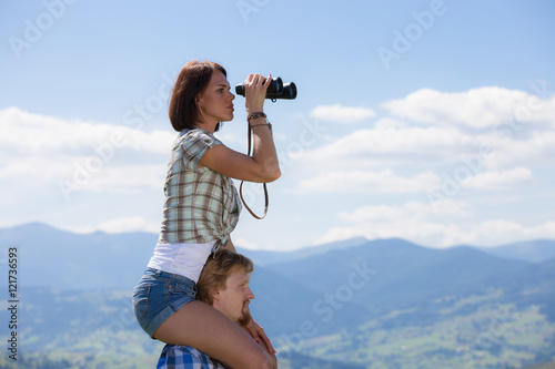 Young couple of travelers looking through binoculars