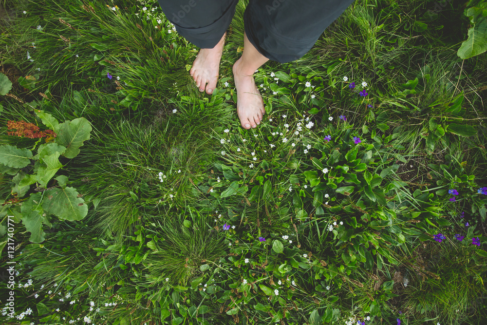 Obraz premium Female standing barefoot on green grass and flowers
