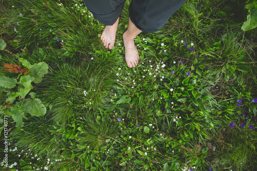 Female standing barefoot on green grass and flowers