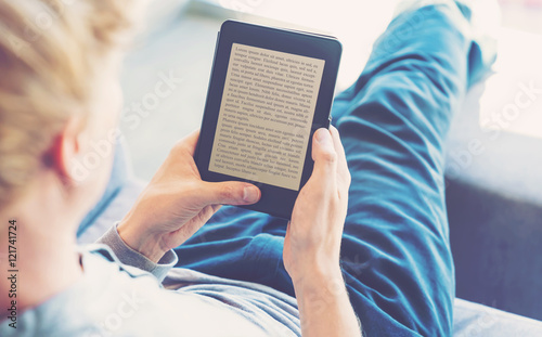 Man reading a book on digital device photo