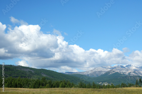 Blue sky and cumulus clouds over the Eastern Sayan Mountains and Mount MunKu-Sardyk. Photo partially tinted. © Евгений Кожевников