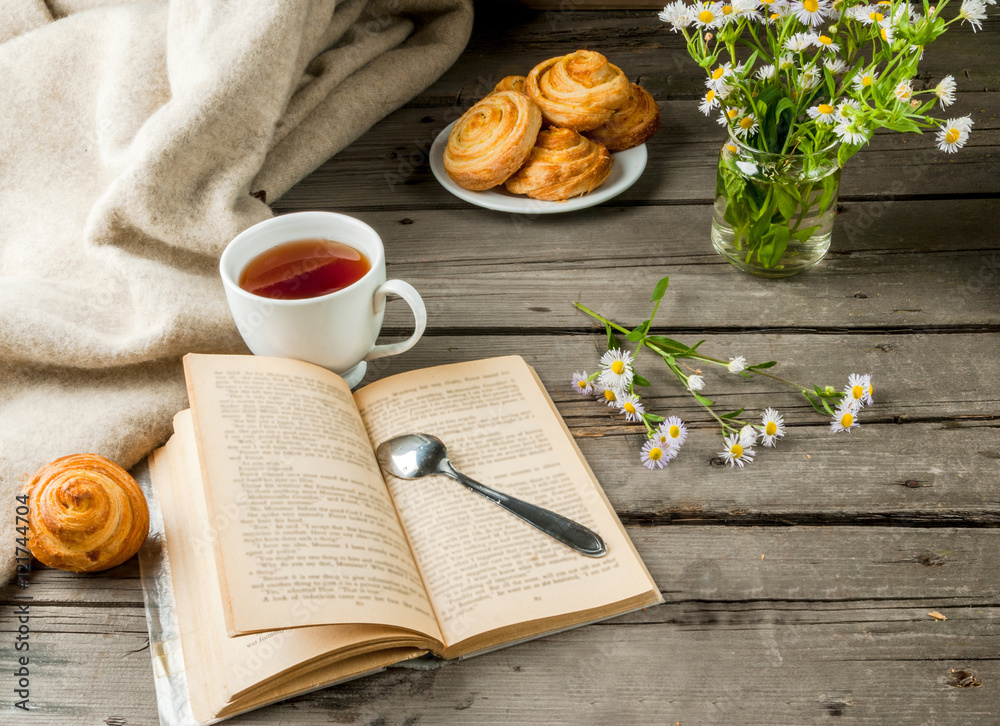 Cozy breakfast in spring or early autumn tea, freshly baked scones and bouquet of field's daisy and fascinating book. Copy space