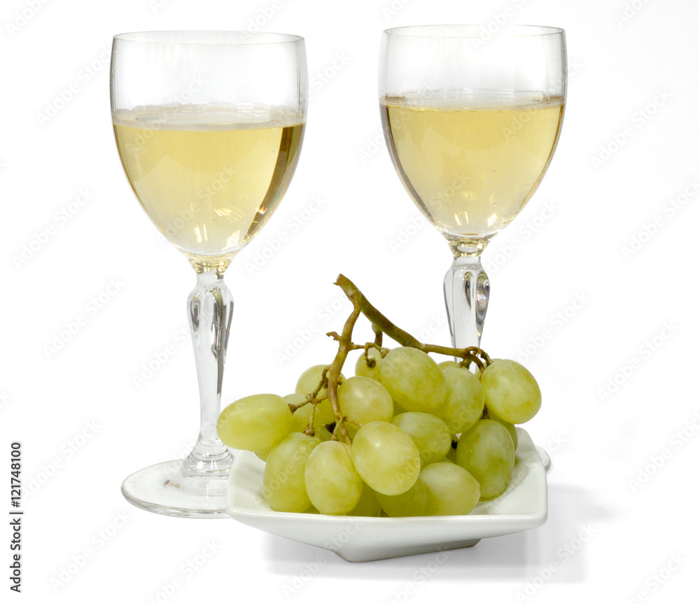 two glasses of sparkling white wine. green grapes on a white plate. isolated on white background two glasses of sparkling white wine. green grapes on a white plate. isolated on white background