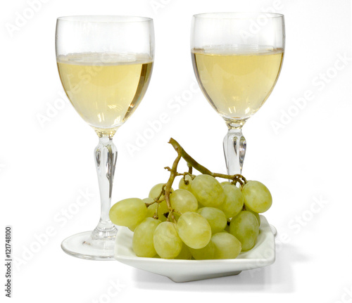 two glasses of sparkling white wine. green grapes on a white plate. isolated on white background