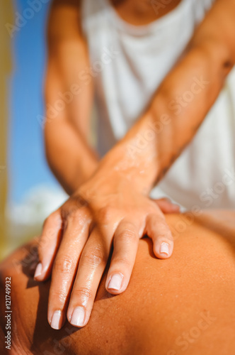 Close up on female masseur hands on man back during a session  sun light background