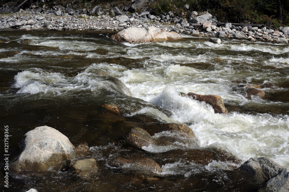 The rapid flow of a mountain river. Photo partially tinted. The rapid flow of a mountain river. Photo partially tinted.