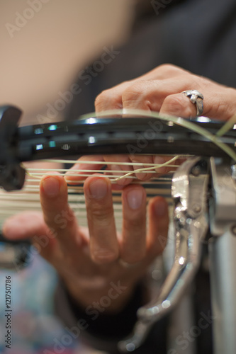 Stringing Machine. Close up of tennis stringer hands doing racket stringing in his workshop