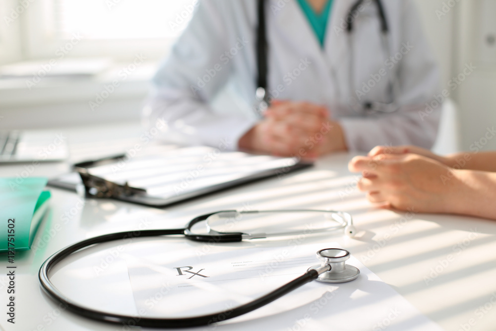 Stethoscope next to hand of doctor reassuring her female patient. Medical ethics and trust concept Stethoscope next to hand of doctor reassuring her female patient. Medical ethics and trust concept