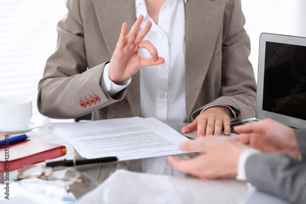 Obraz premium Group of business people or lawyers at meeting discussing contract papers. Woman showing ok sign