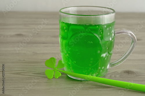 Green liquid in a beer mug displayed with a four leaf clover 
