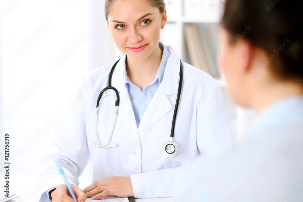 Friendly smiling doctor and patient sitting at the table. Very good news and high level medical service concept. Friendly smiling doctor and patient sitting at the table. Very good news and high level medical service concept.