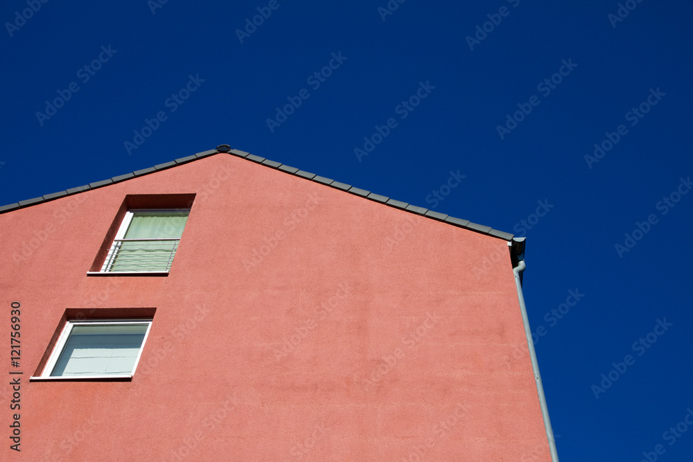House with a red facade against a blue sky in Aachen, Germany