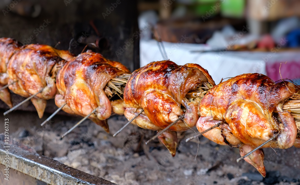 Free range chicken fire roasting traditional way on skewer at Thai cafe background. Selective focus Free range chicken fire roasting traditional way on skewer at Thai cafe background. Selective focus