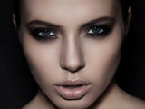 Beautiful woman model smokey eyes makeup closeup on black