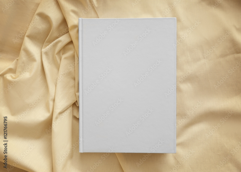 White closed book on light crumpled sheet White closed book on light crumpled sheet