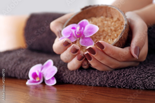 Female hands with brown manicure holding sea salt in bowl, closeup