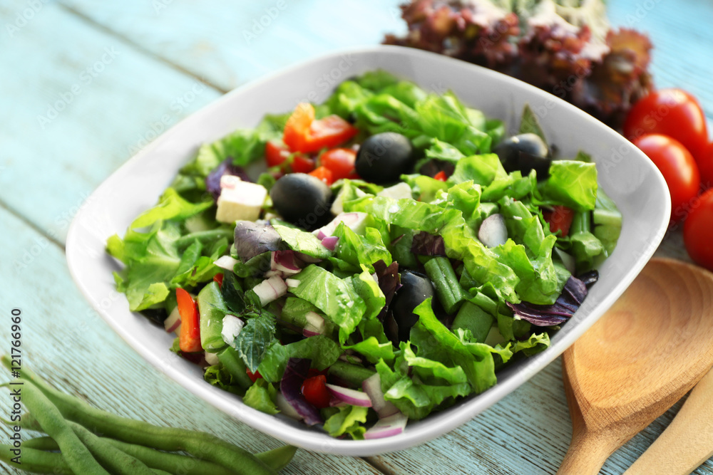 Fresh salad in bowl on wooden background