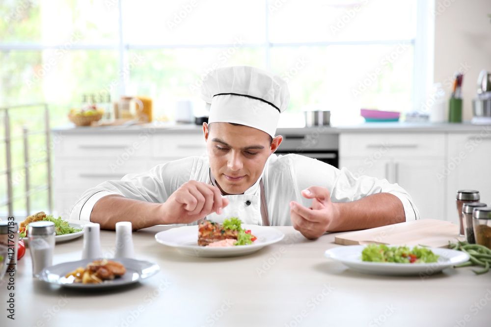 Young chef cook decorating meat dish in kitchen Young chef cook decorating meat dish in kitchen