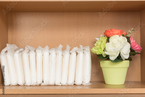  menstrual pad (sanitary)  and artificial flower on shelf 