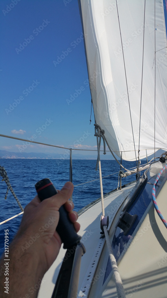 Mano su maniglia winch intenta a cazzare il fiocco Mano su maniglia winch intenta a cazzare il fiocco
