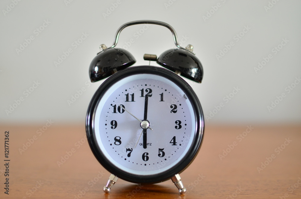 The black alarm clock is showing time at six o'clock The black alarm clock is showing time at six o'clock