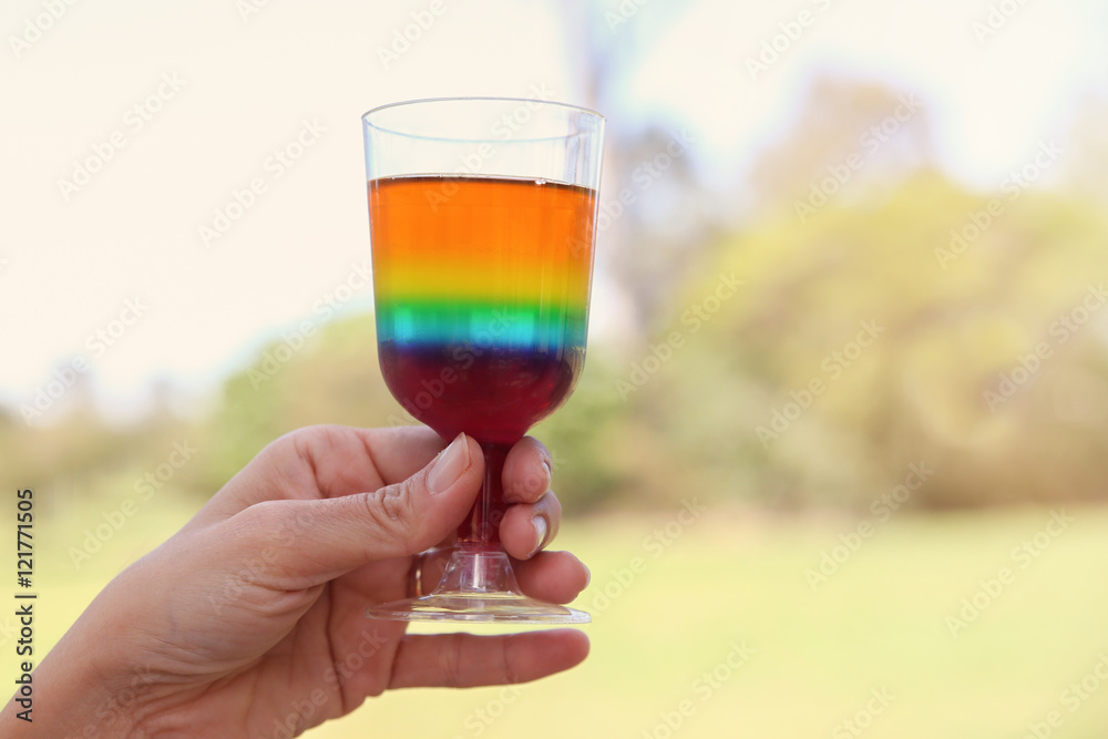 hand holding a glass of rainbow jelly in the park hand holding a glass of rainbow jelly in the park