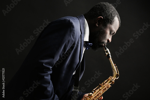 Photography African American jazz musician playing the saxophone on grey background