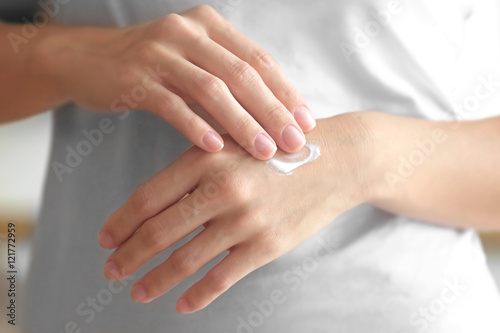 Fototapeta Naklejka Na Ścianę i Meble -  Young woman applying cream onto hands