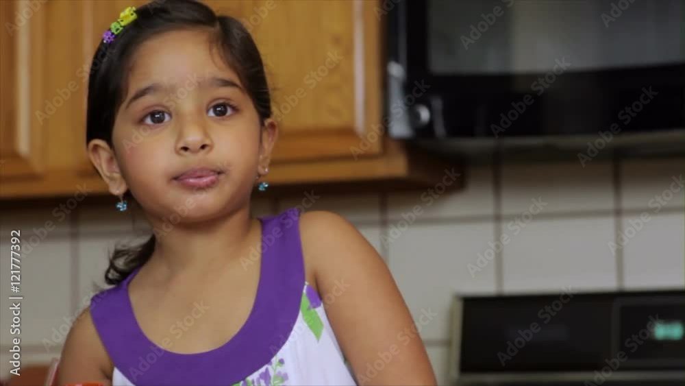 A cute little in a kitchen girl drinking juice. A cute little in a kitchen girl drinking juice.