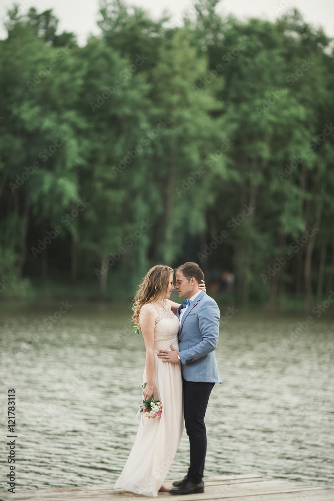 Elegant beautiful wedding couple posing near a lake at sunset Elegant beautiful wedding couple posing near a lake at sunset