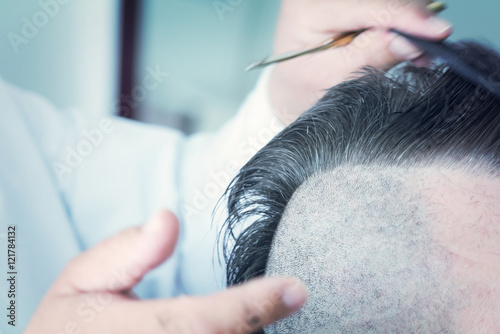 Barber makes a mohawk hairstyle of a adult bearded man. Toned photo