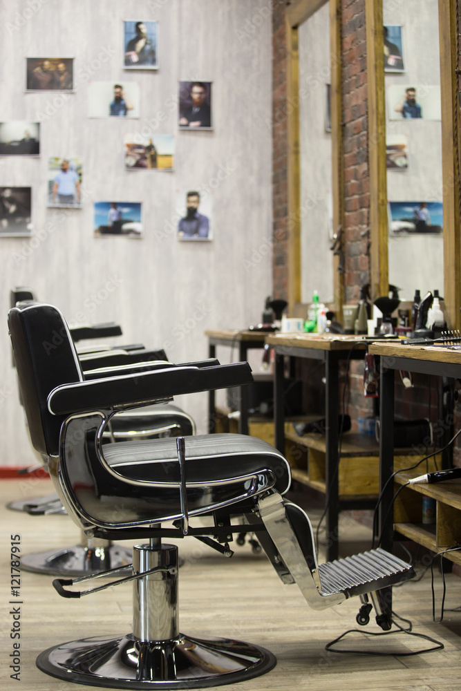Row of black leather chairs in modern barber shop interior. Vertical indoors image