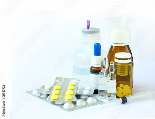 cold medicines on a light background - pill, syrup, drop, ampoule, syringe