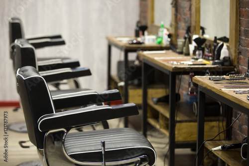 Row of black leather chairs in modern barber shop interior. Horizontal indoors shot © fizkes