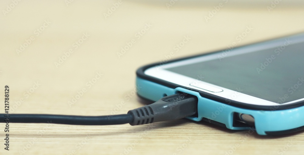 charging smart phone on wooden table charging smart phone on wooden table