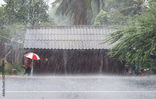 Fotografie Old woman holding umbrella at front of wooden house