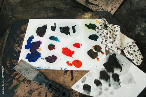 Colorful mixed oil paint smears with palette-knife. Samples of different colors on paper palette. Close-up of artist workplace with swatches