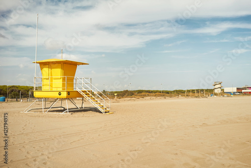 Bright yellow lifeguard post and other distant beach structures on a quiet day with no people around