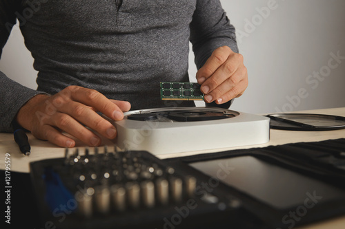 Athletic man in a dark gray henley shirt installing memory chips into computer