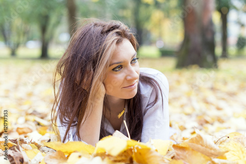 Portrait of young woman lying on autumn leaves. photo