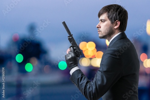 Foto Secret agent or spy holds pistol in hand at dusk.