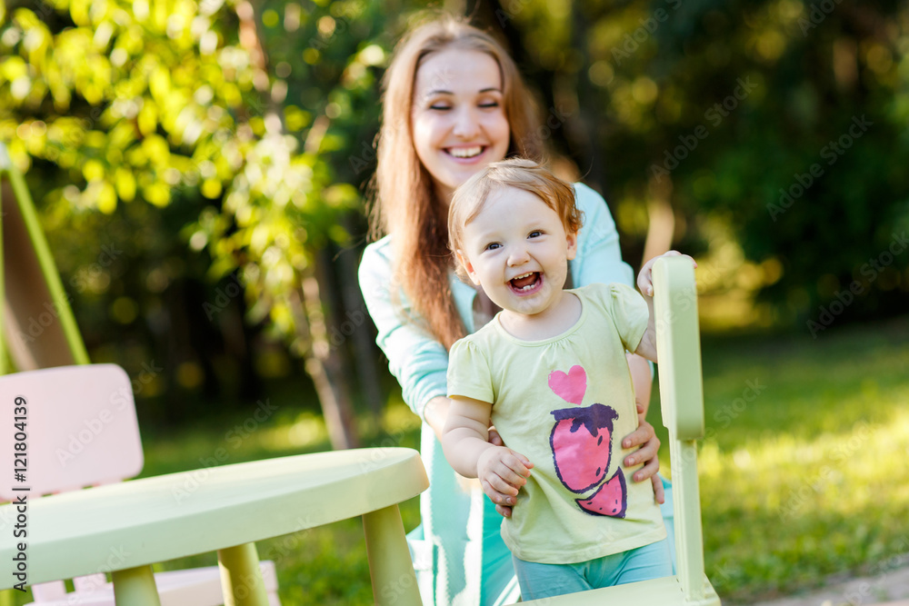 Fototapeta premium Happy mother with daughter sitting on children's chair