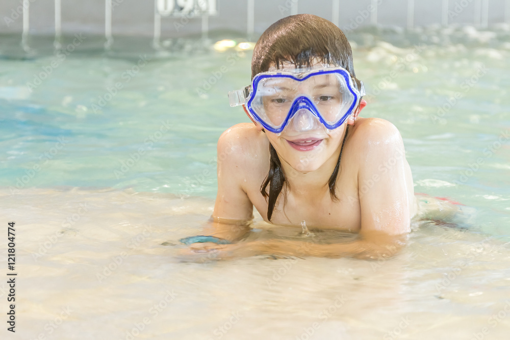 young happy smiling boy swimming in water pool