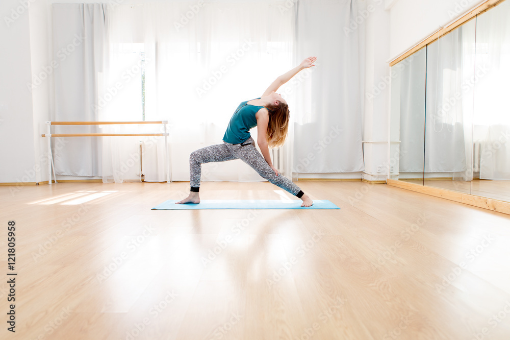 Woman doing high lunge yoga asana in light spacious studio