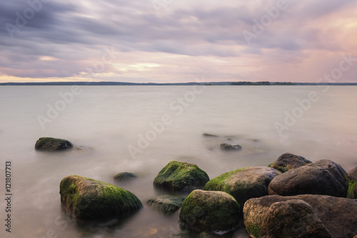 Stones in lake over sunset, long time exposure effect.