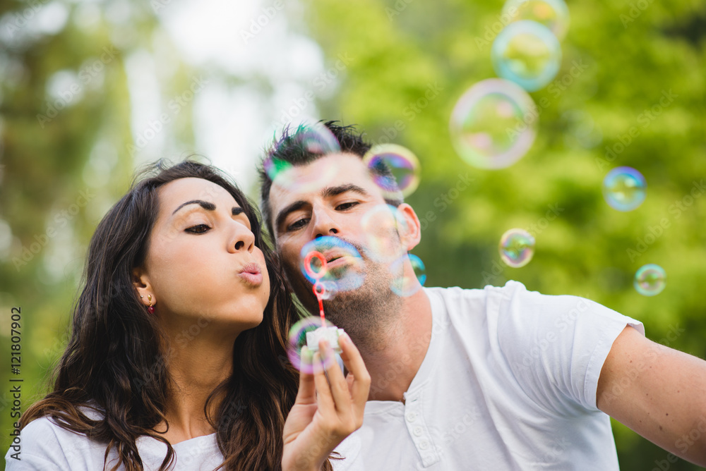 Young couple blowing bubbles. Man and woman dating and having fun at the park.