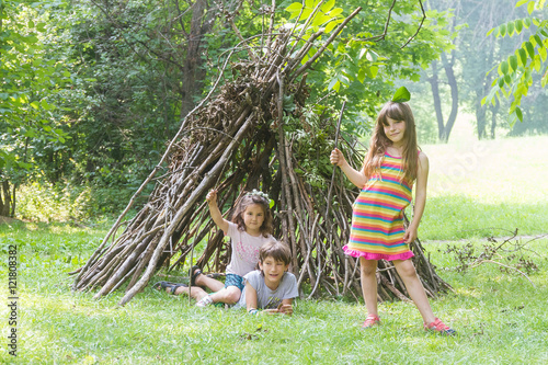 kids playing next to wooden stick house looking like indian hut,